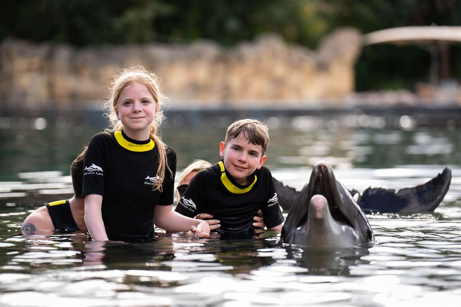 Siblings Lottie Scott, 14, and Tommy Scott, 11, with a dolphin during the Dreamflight visit to Discovery Cove in Orlando (James Manning/PA)