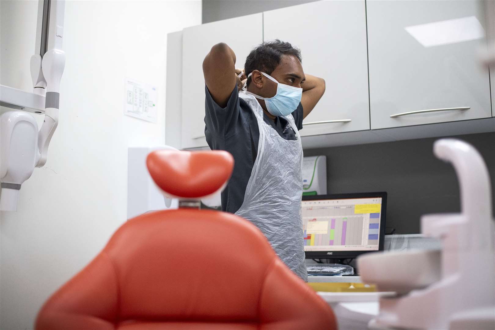 Dentist Dr Roy Woodhoo puts on PPE before treating a patient at Woodford Dental Care in north London as the practice opens up for the first time since the UK went into coronavirus lockdown (Victoria Jones/PA)