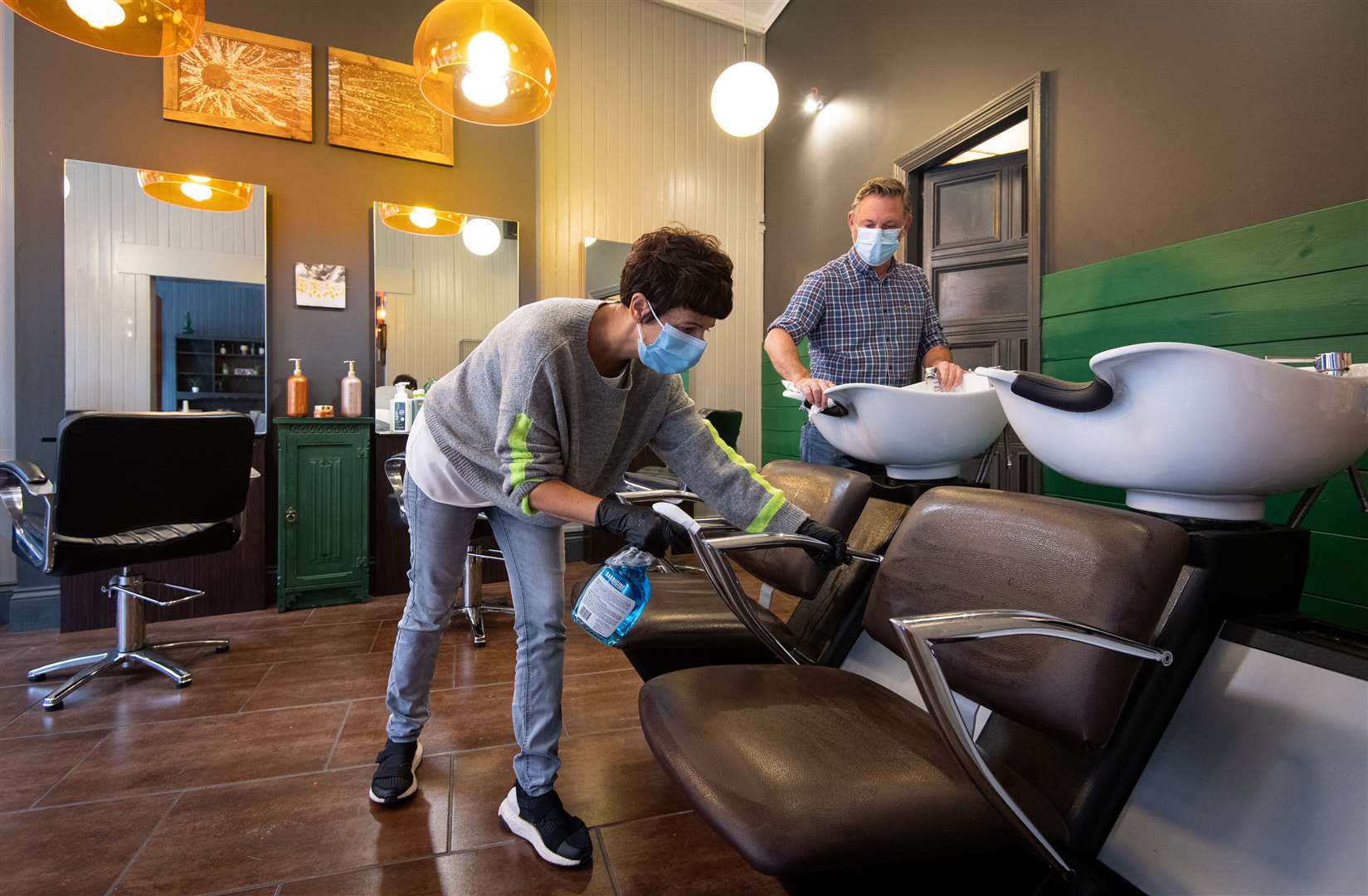 Maria Demetriou-Clamp and Robin Dignall disinfect chairs at their hair salon ‘Hair @ 1RD’ in Leicester (Joe Giddens/PA)