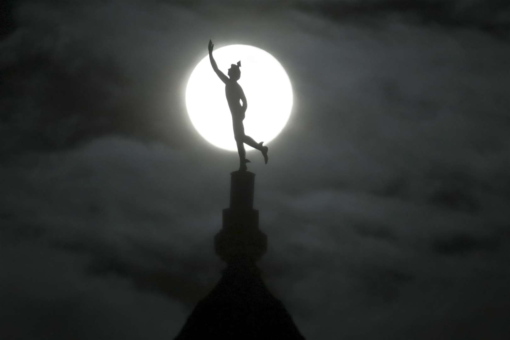 The supermoon rises behind a statue of the Roman god Mercury mounted on top of a hotel tower in Nashville (Mark Humphrey/AP)