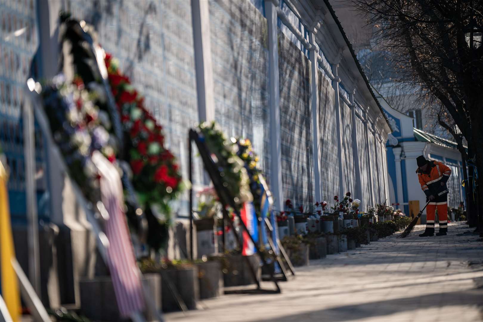 A city worker cleans along the wall of remembrance of the fallen for Ukraine in Kyiv (Aaron Chown/PA)