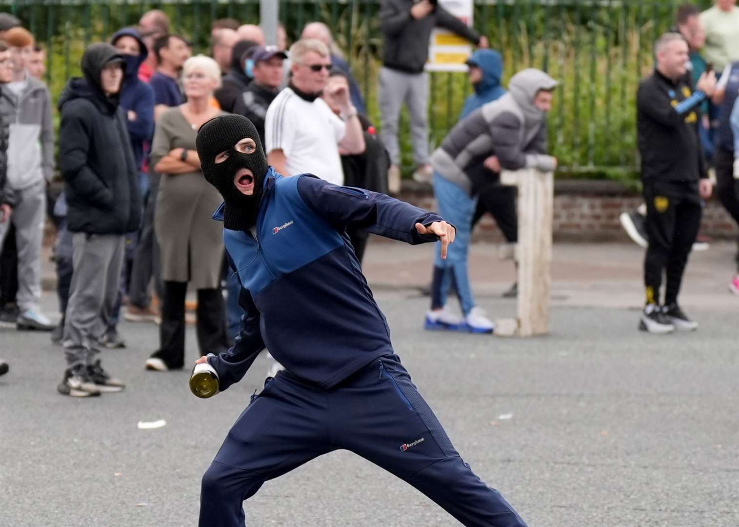 A youngster throws a bottle towards gardai officers during a stand off with protesters at Coolock (Niall Carson/PA)