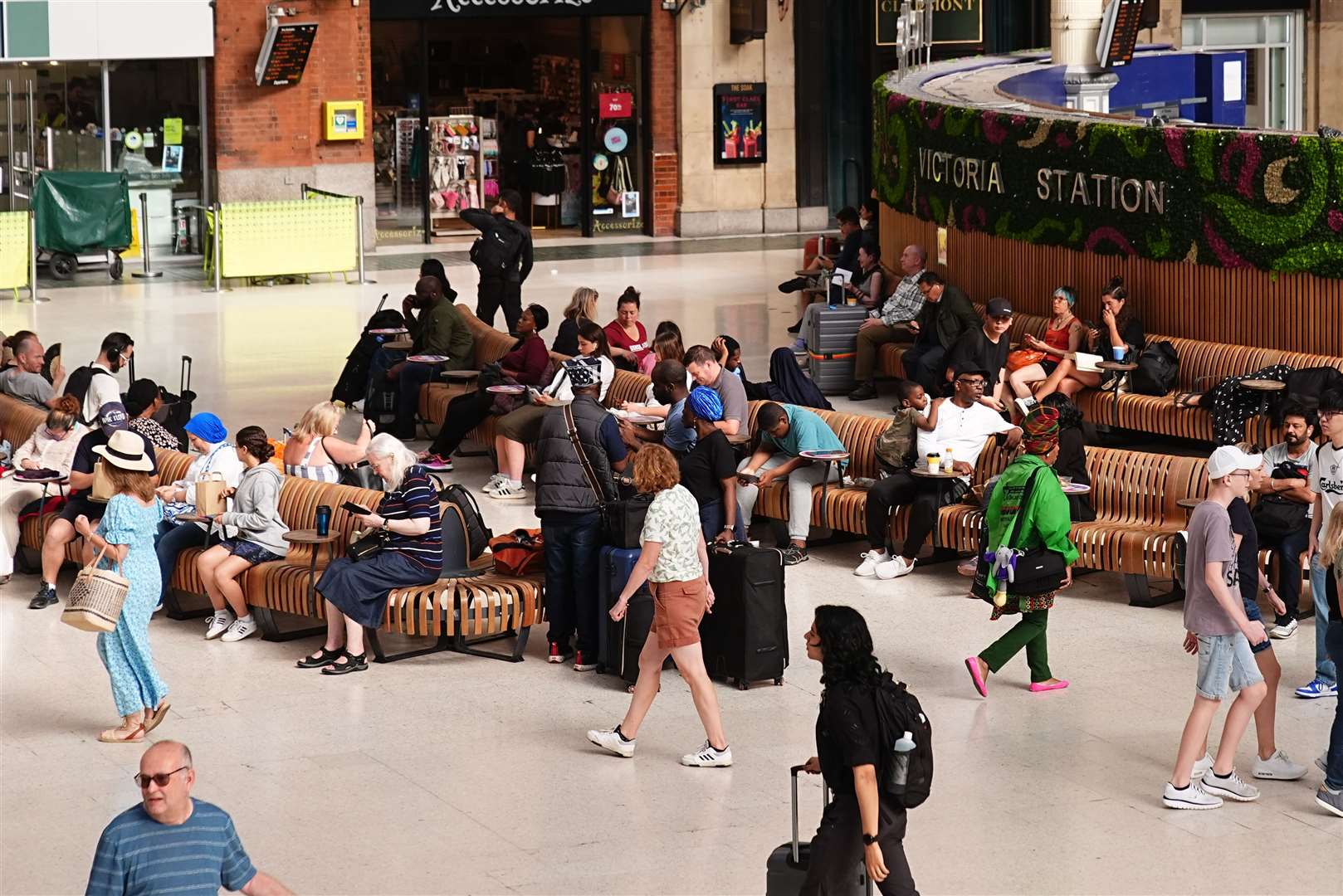 Passengers wait at Victoria railway station in London as services are affected by the IT outage (Aaron Chown/PA)