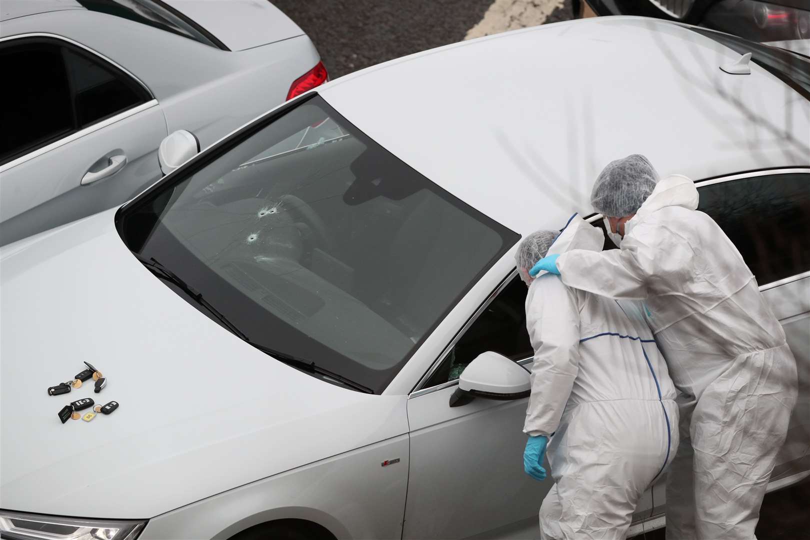 Police forensics officers examine a silver Audi with bullet holes in its windscreen at the scene near junction J24 of the M62 in Huddersfield where a man died in a police shooting (Peter Byrne/PA)