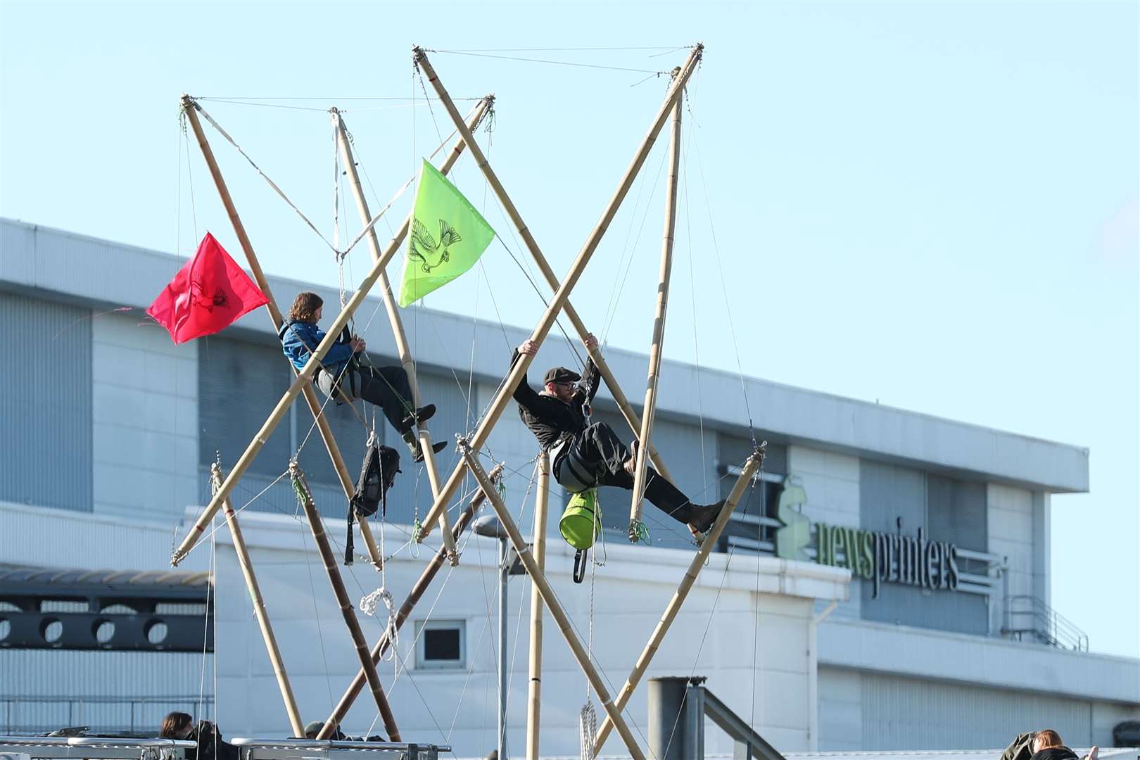 Two protesters use bamboo lock-ons to block the road outside the Newsprinters printing works at Broxbourne, Hertfordshire (Yui Mok/PA)