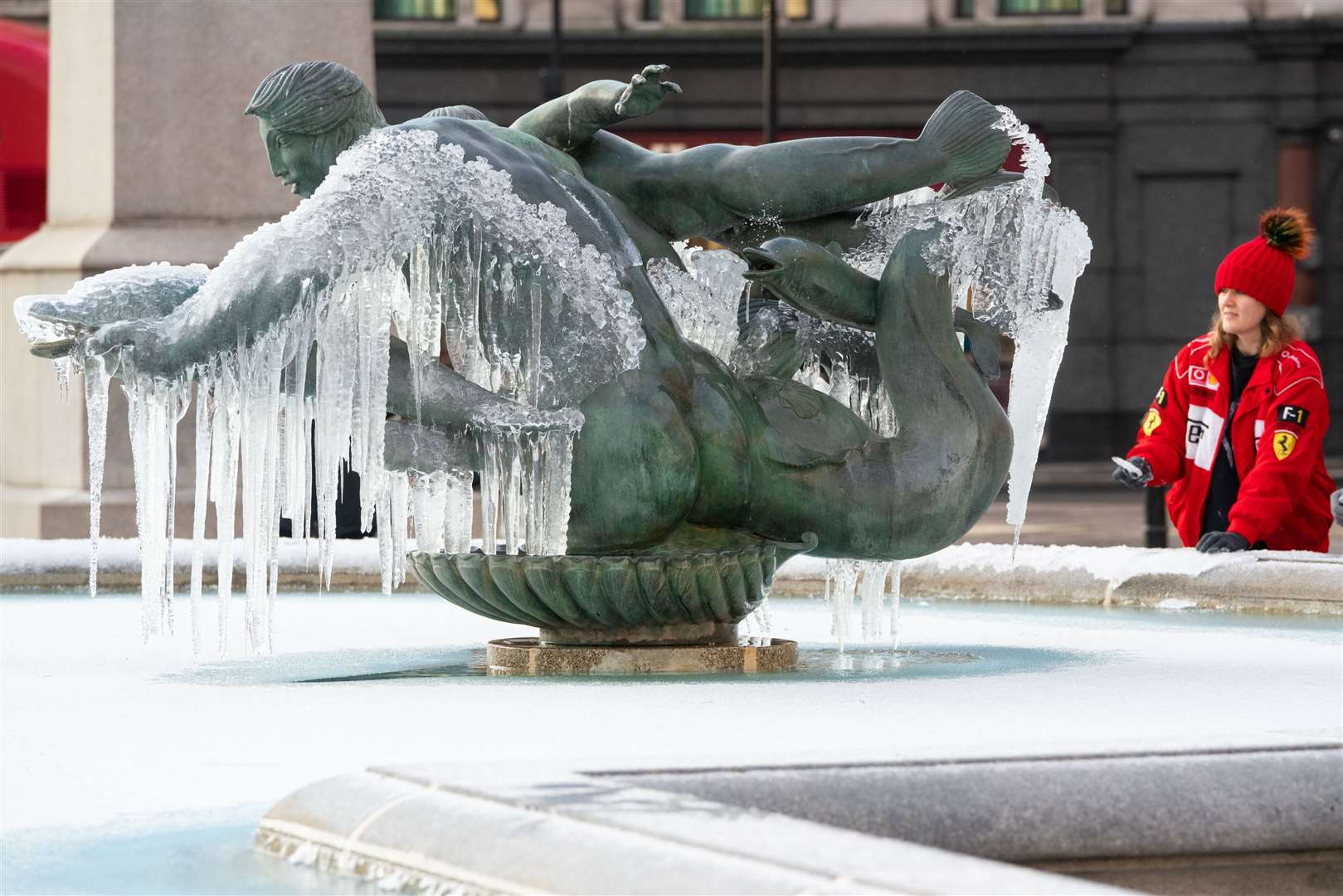 A woman looks at frozen fountains in Trafalgar Square, London (Dominic Lipinski/PA)