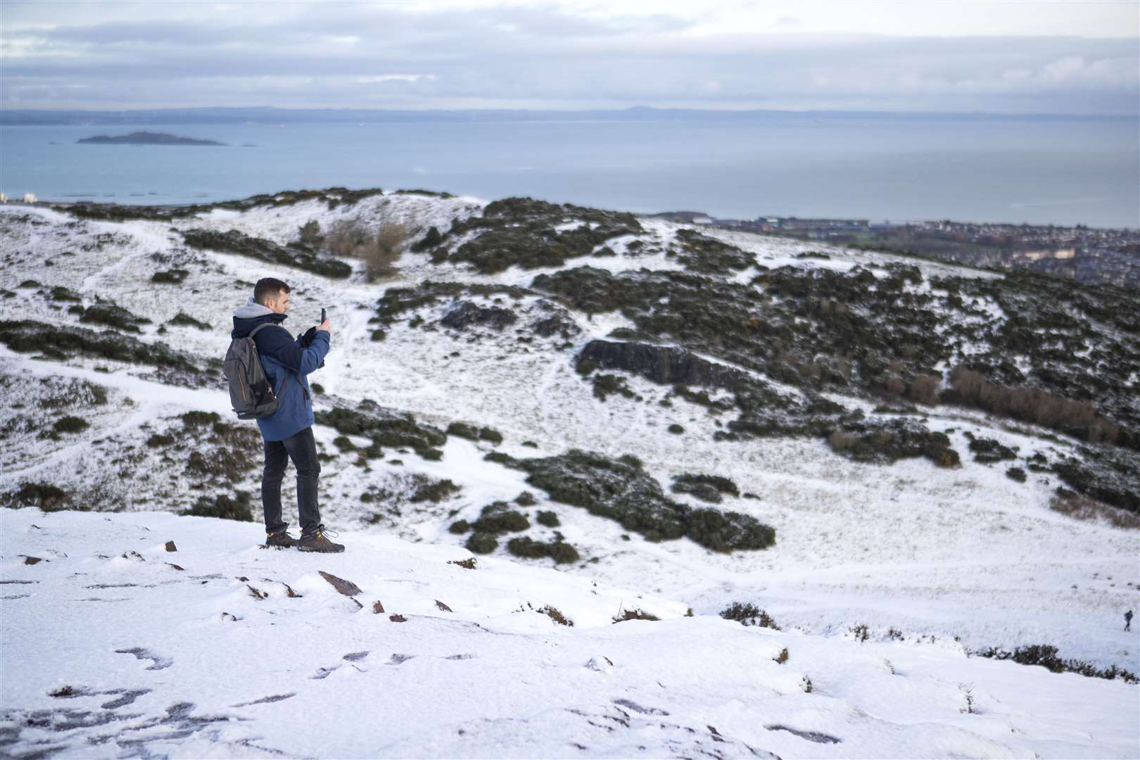 A walker stopped to take photos of the view as he climbed Arthur’s Seat in Edinburgh (Jane Barlow/PA)