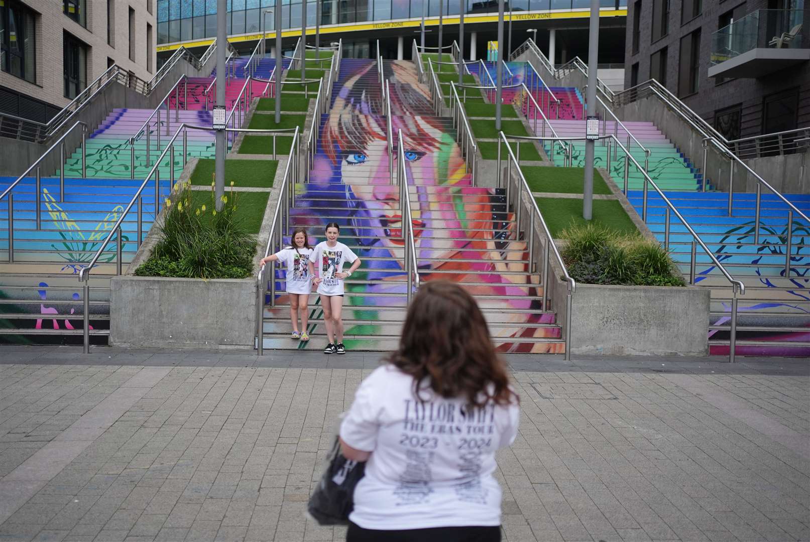 Eight-year-old Gracie Hiles and sister 12-year-old Jessica Evans pose as their mother takes their photograph at the Swiftie Steps and murals at Wembley (Yui Mok/PA)