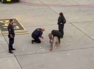 The man and the airport workers picked some of the money up from the ground after it was reportedly thrown. Picture: SWNS