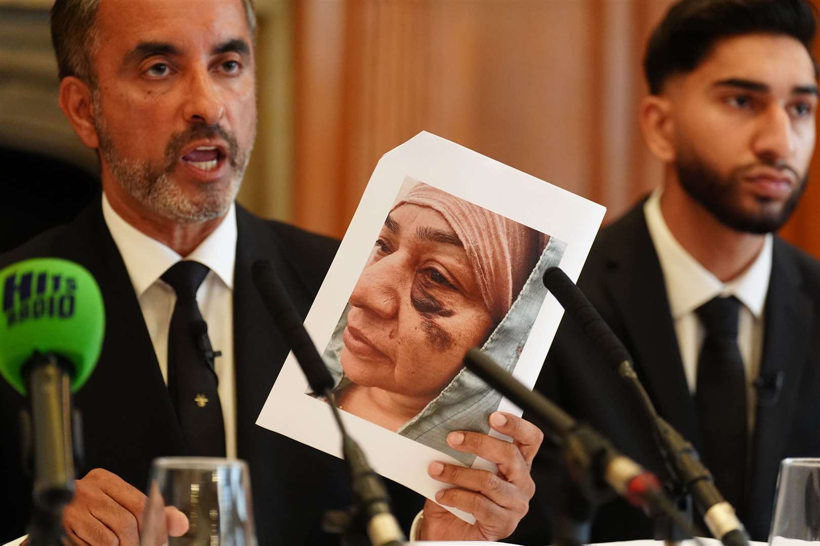 Solictor Aamer Anwar, holds up a picture of Shameem Akhtar as her son Fahir Amaaz, 19, looks on during the press conference (Owen Humphreys/PA)