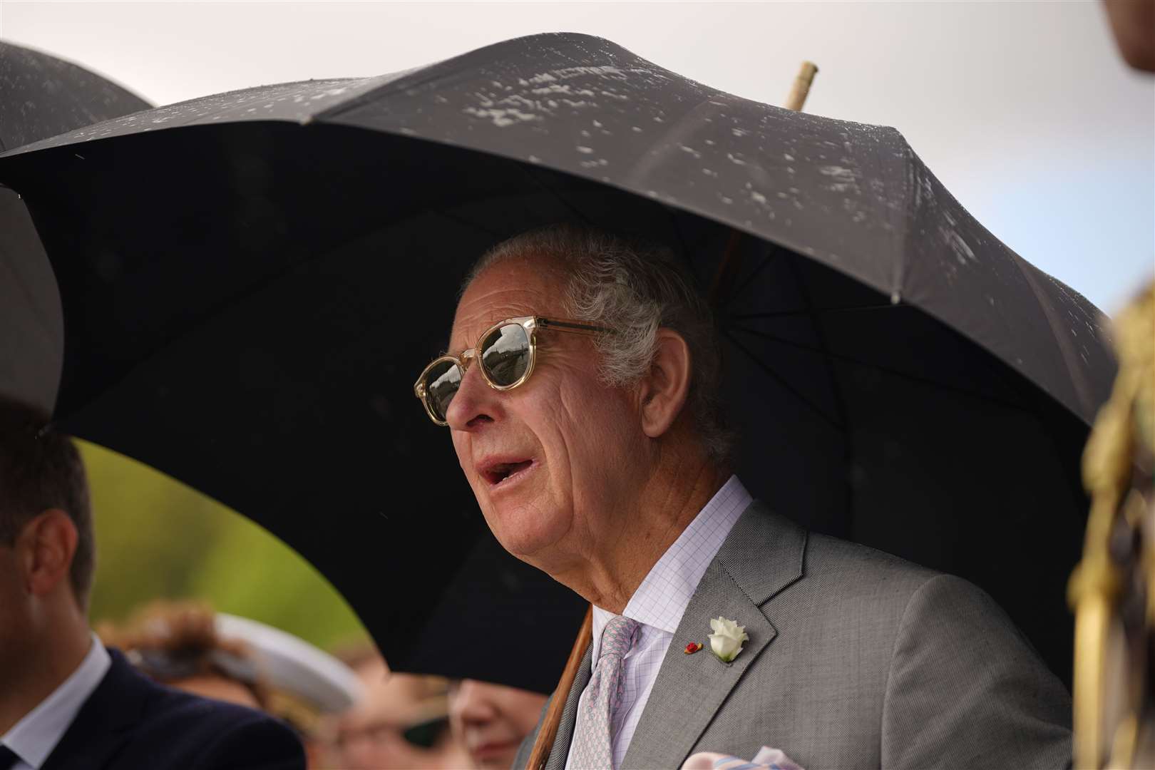 Charles required sunglasses and an umbrella as he watched the flypast from the HMS Iron Duke (Yui Mok/PA)