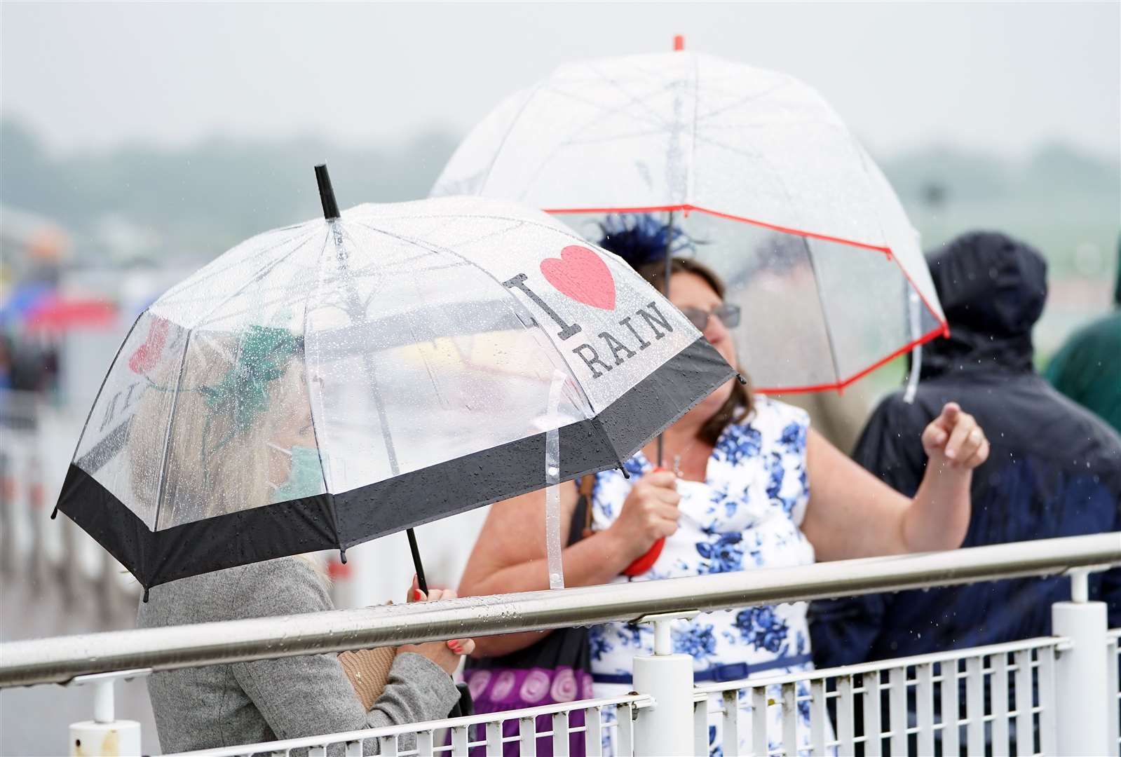 Racegoers shelter from the rain under umbrellas during day one of the Cazoo Derby Festival at Epsom Racecourse (Mike Egerton/Jockey Club/PA)