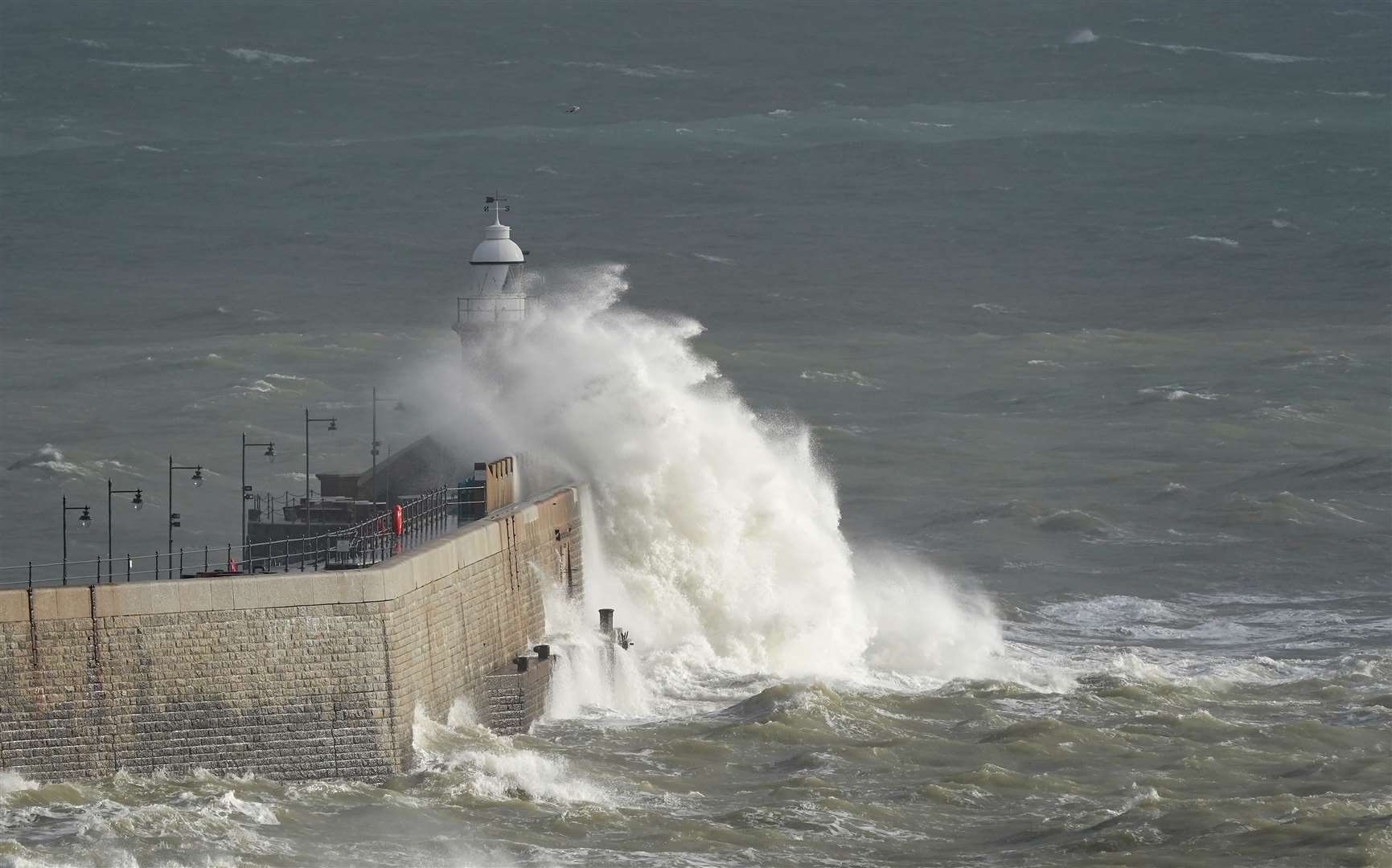 Waves crash over the harbour arm in Folkestone, Kent (PA)