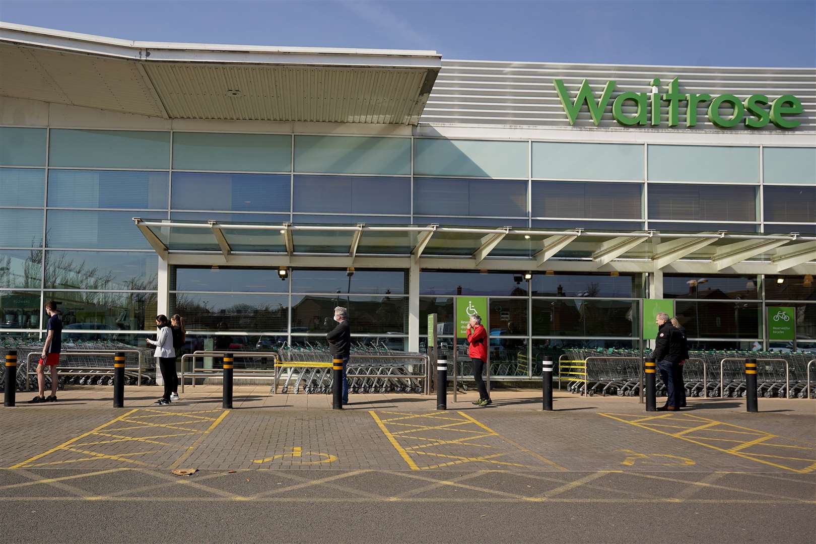 People observe social distancing while queuing at a Waitrose supermarket in Lichfield, the day after Prime Minister Boris Johnson called on people to stay at home and avoid all non-essential contacts and travel in order to reduce the impact of the coronavirus pandemic (Morgan Harlow/PA)