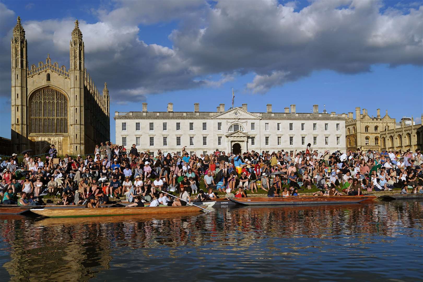 People sit on the banks of the River Cam, in punts on the water and on the lawns of King’s College in Cambridge, as they listen to The King’s Men perform (Joe Giddens/PA)