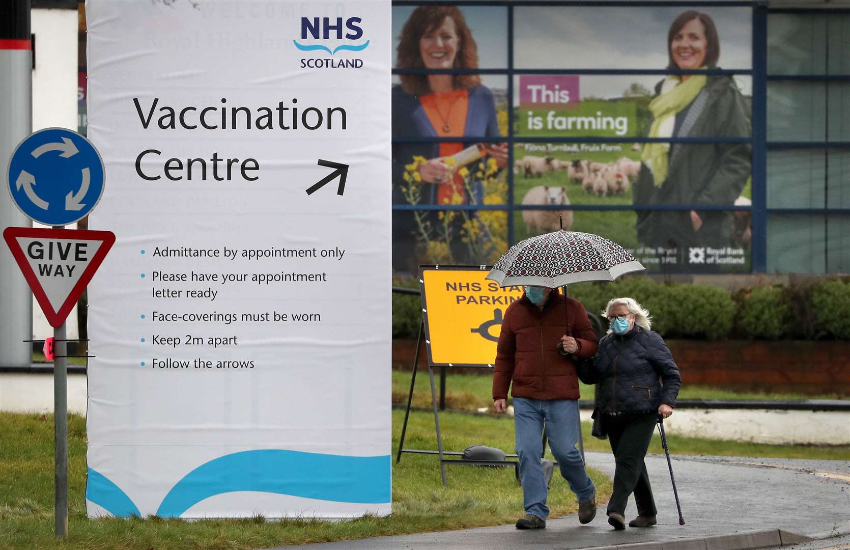 Meanwhile, these people walking past a Vaccination Centre sign at the Royal Highland Show ground in Edinburgh, needed an umbrella (Andrew Milligan/PA)