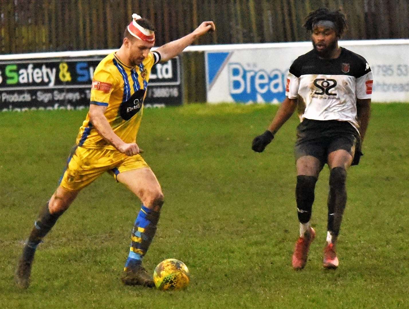 Sittingbourne captain Kane Rowland clears under pressure from Faversham's Emmanuel Oluwasemo. Picture: Ken Medwyn