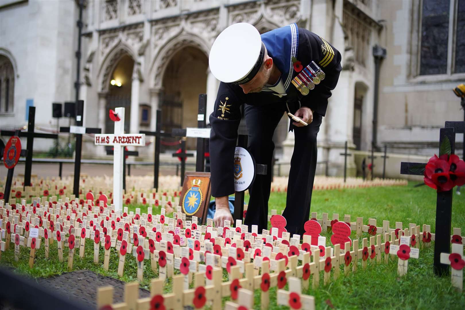 A member of the Royal Navy places a memorial cross at the Field of Remembrance at Westminster Abbey in London (Aaron Chown/PA)