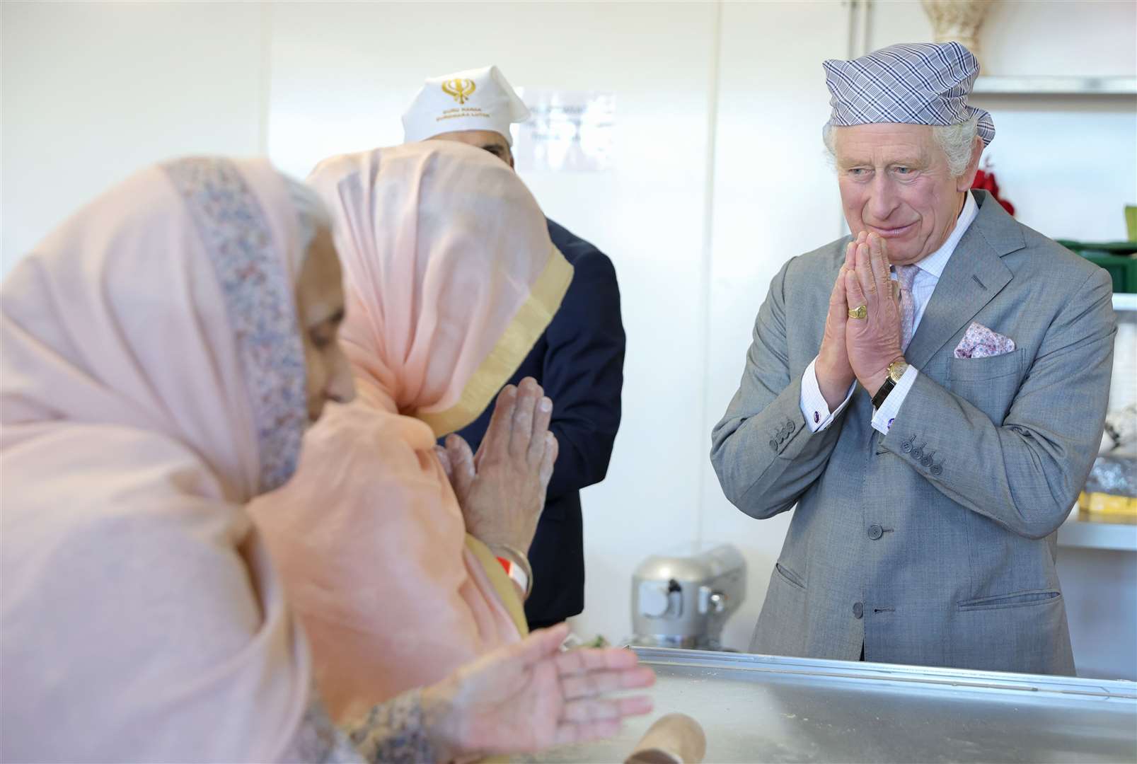 Charles makes the traditional namaste gesture as he meets volunteers during a visit to the newly built Guru Nanak Gurdwara Sikh temple in Luton (Chris Jackson/PA)