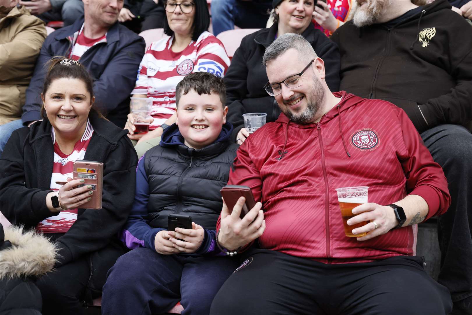 Fans check their phones as the UK-wide emergency alert system shows on their lock screen as it is tested during the Betfred Super League match at the DW Stadium, Wigan (Richard Sellers/PA)