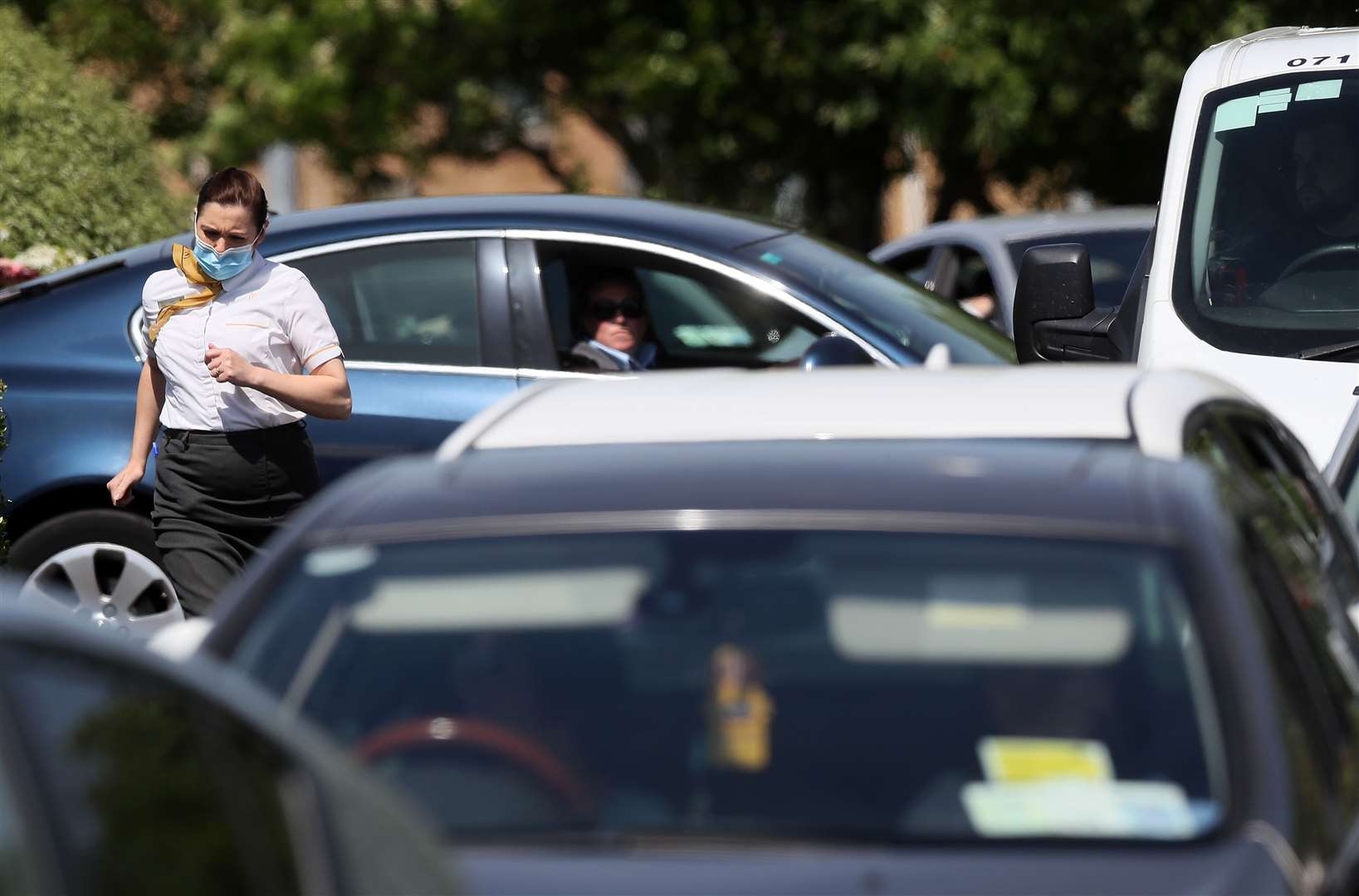 A McDonald’s employee among cars as they queue at a drive-thru (Brian Lawless/PA)