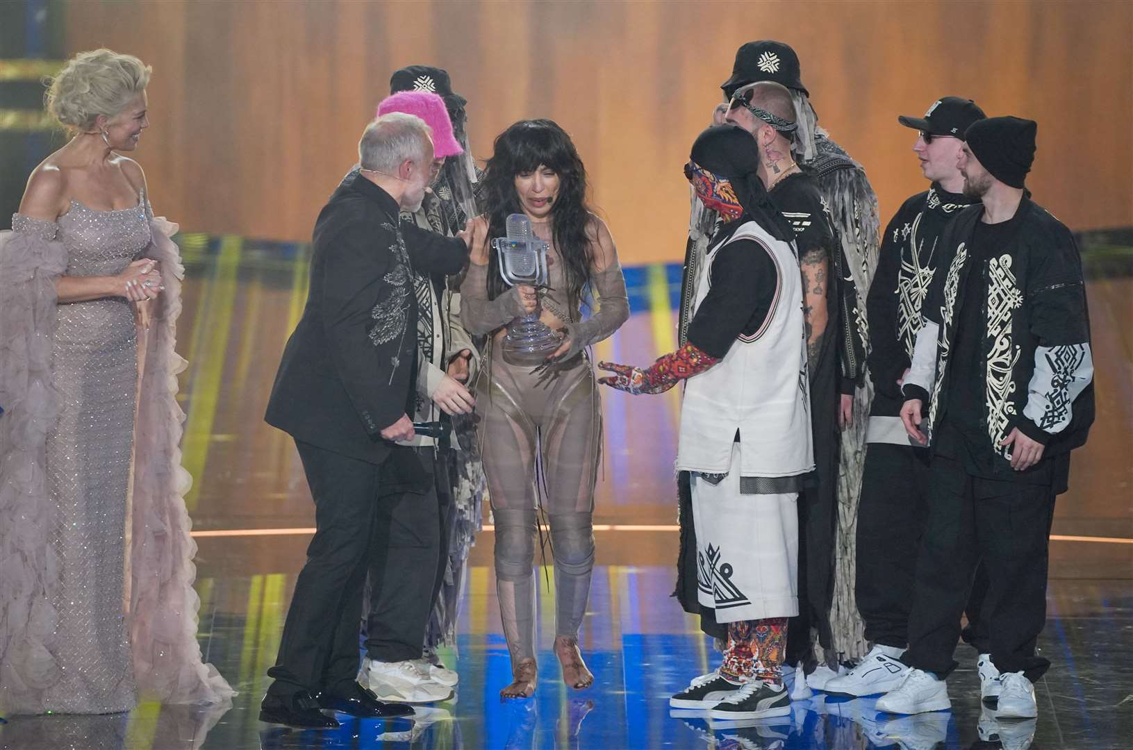 Loreen is presented with the trophy by Kalush Orchestra and Graham Norton (Peter Byrne/PA)