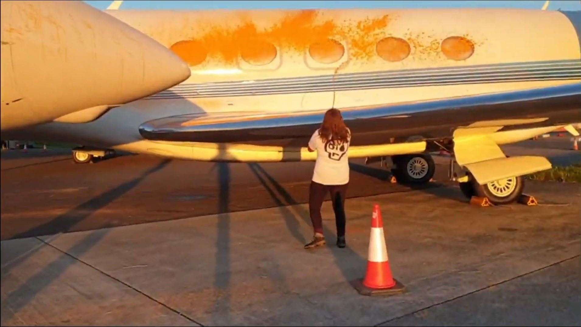 An activist spraying the fuselage and windows of a plane (Just Stop Oil/PA)
