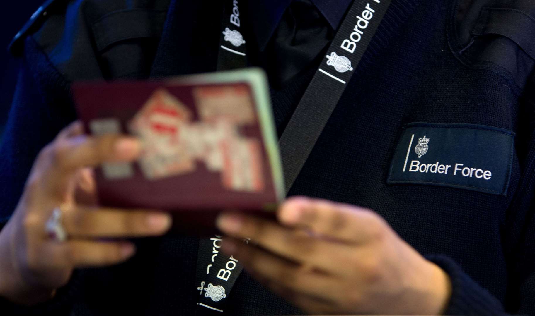 A Border Force worker inspecting a passport