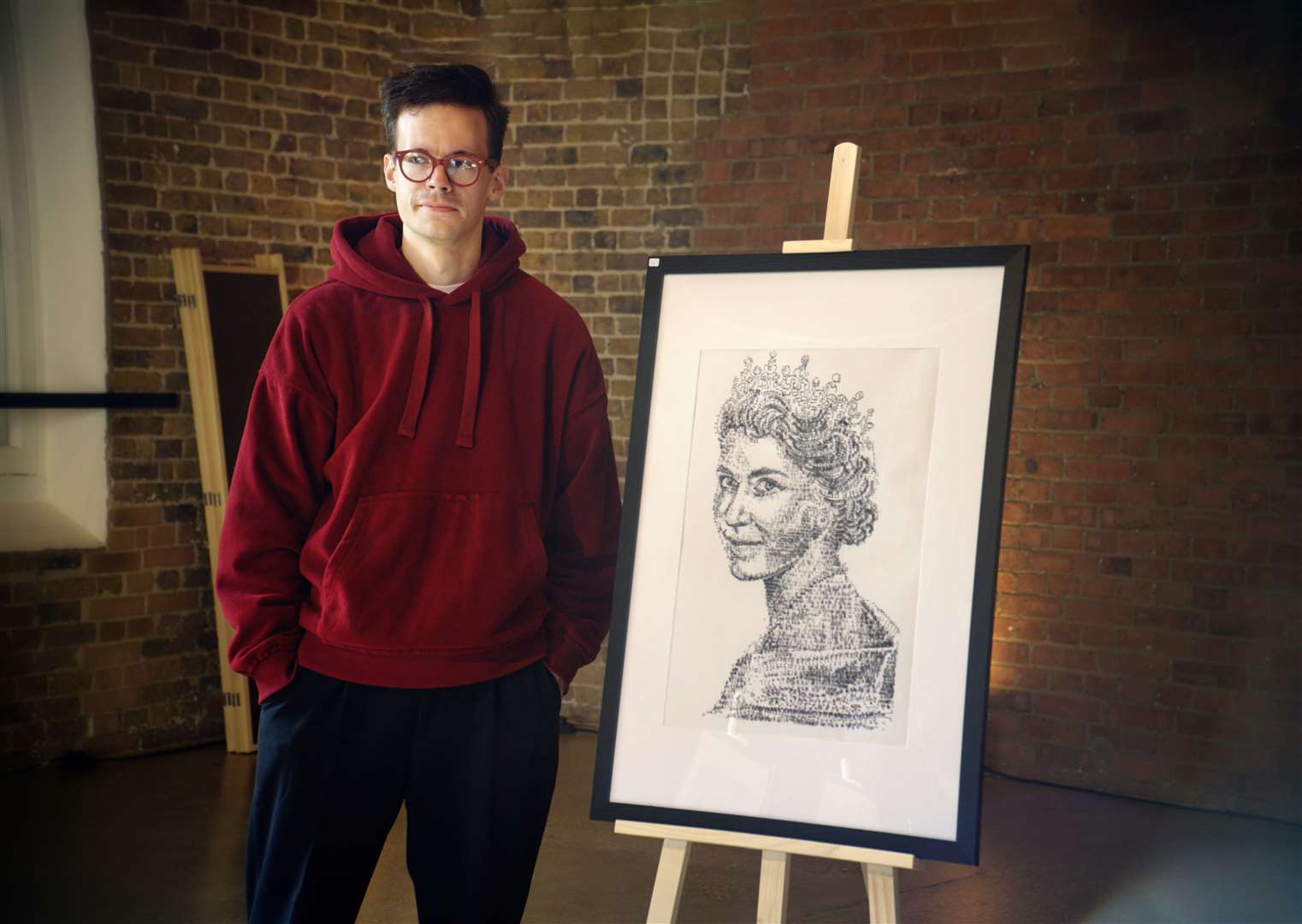 Artist James Cook next to his portrait of the Queen (James Cook/PA)