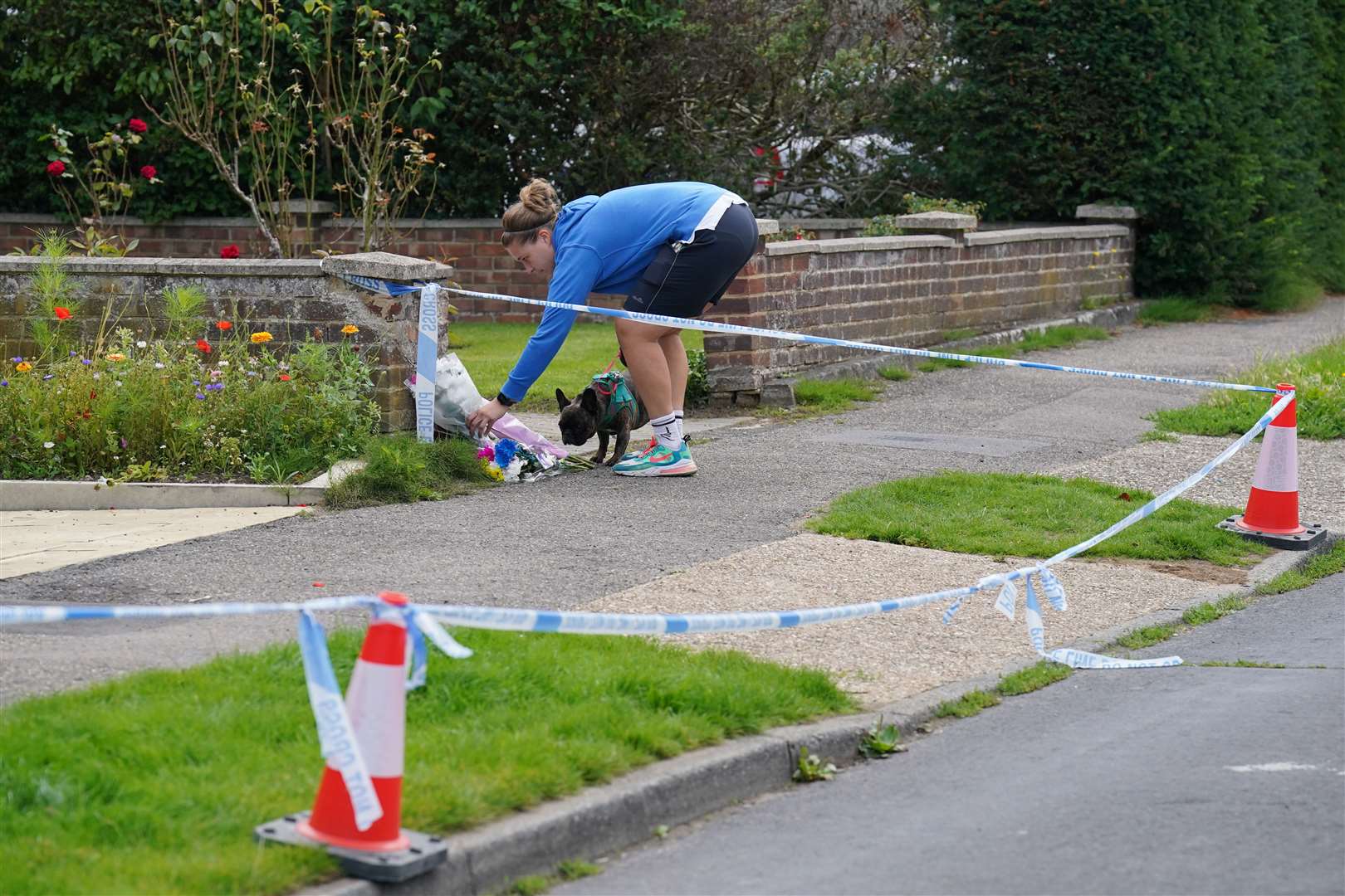 A person leaves flowers outside the house (Jonathan Brady/PA)