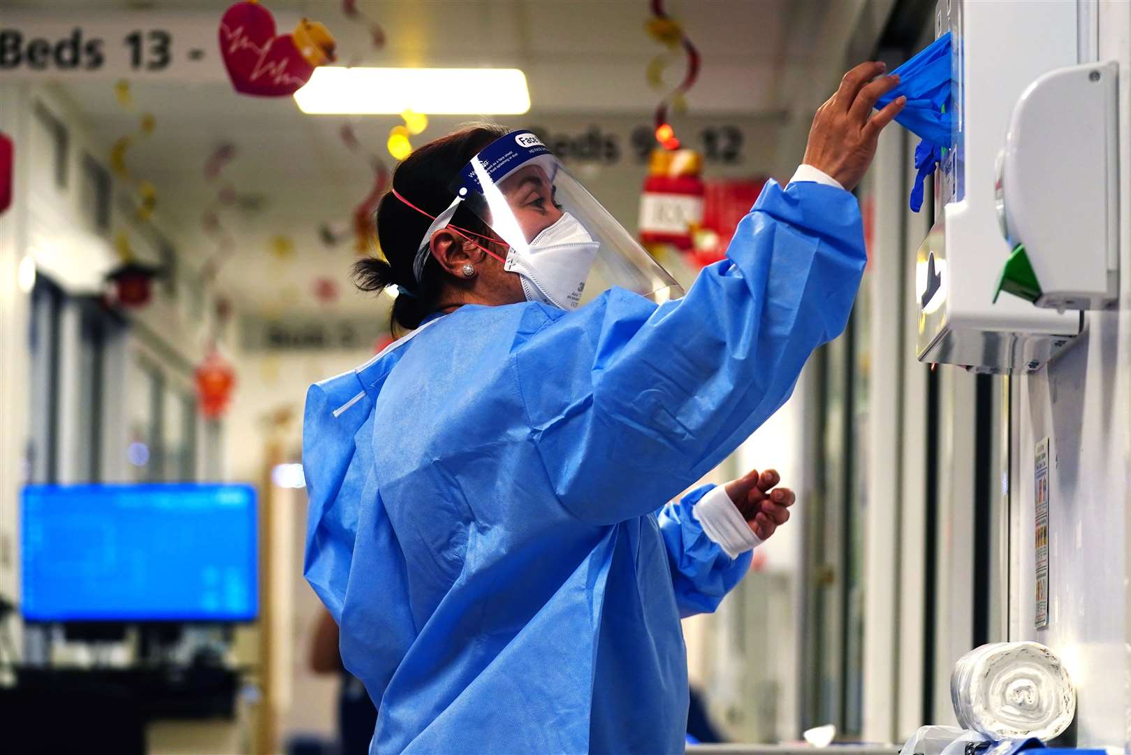 A nurse puts on PPE on a ward for Covid patients at King’s College Hospital, London (Victoria Jones/PA)