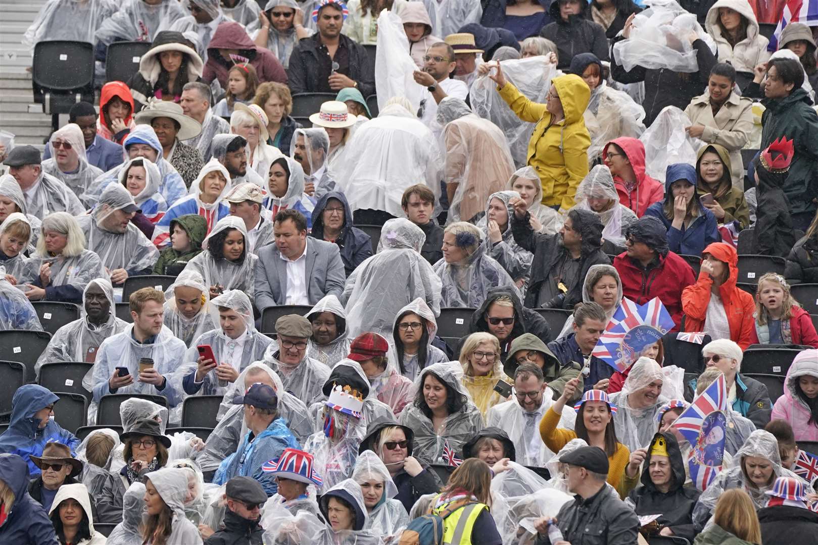 Crowds wore rain ponchos in the grandstand opposite Buckingham Palace ahead of the coronation ceremony (Owen Humphreys/PA)