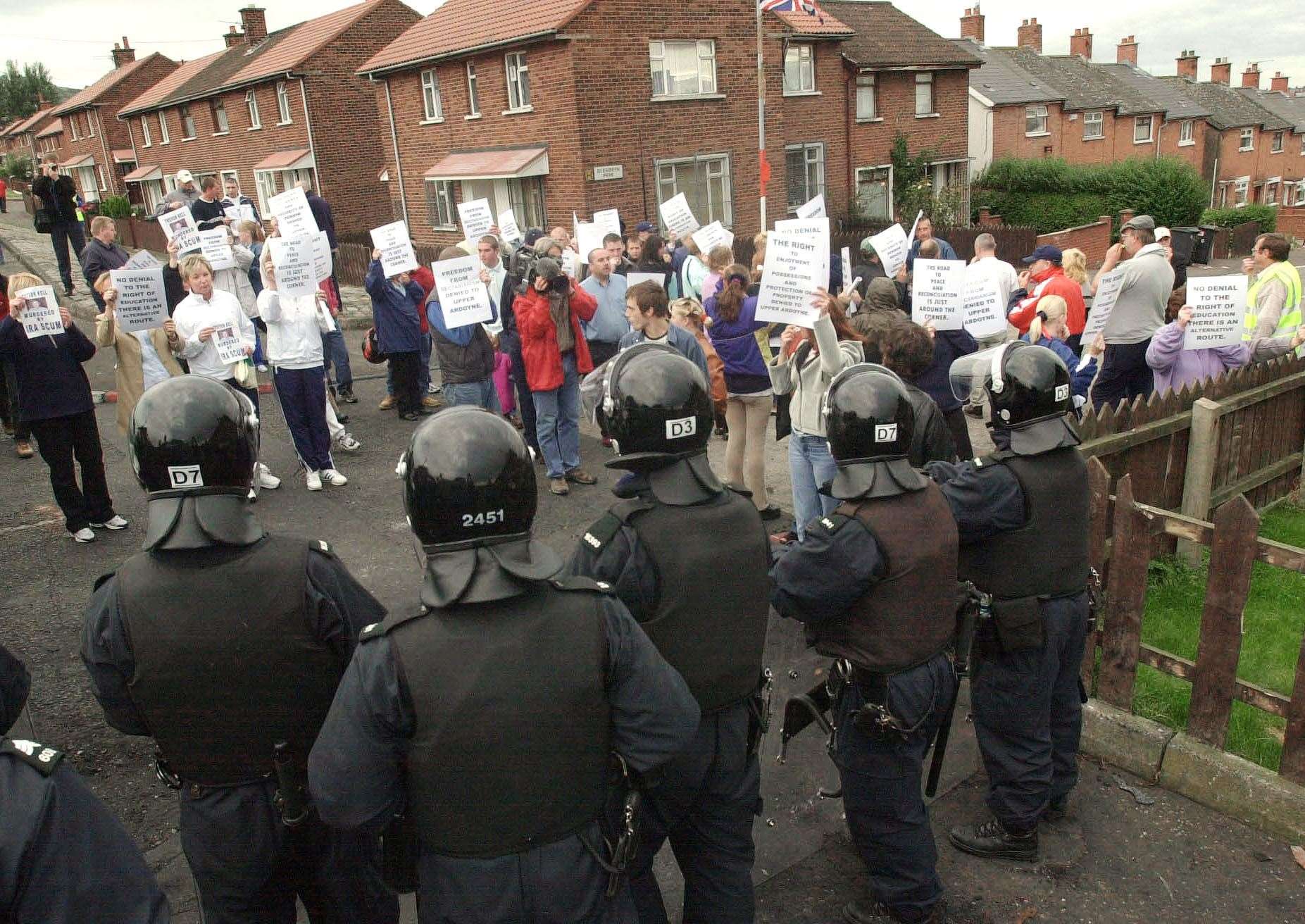 Protestant residents protest behind an RUC cordon as they demonstrate against pupils and parents making their way to the Holy Cross Girls School in Belfast (John Giles/PA)