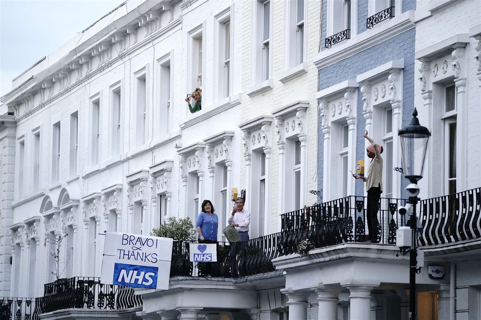 People stand on their balconies and lean from windows near to the Chelsea and Westminster Hospital (Aaron Chown/PA)