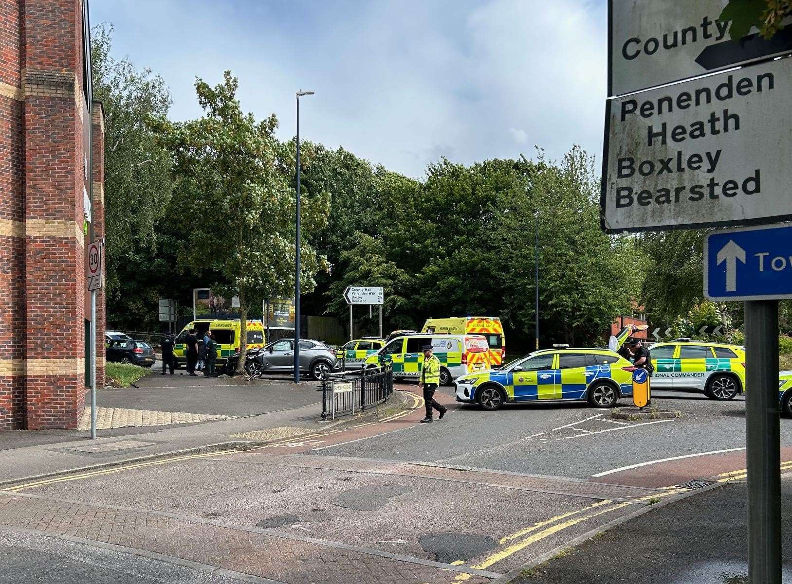 A car has crashed through railings into a tree on a busy roundabout