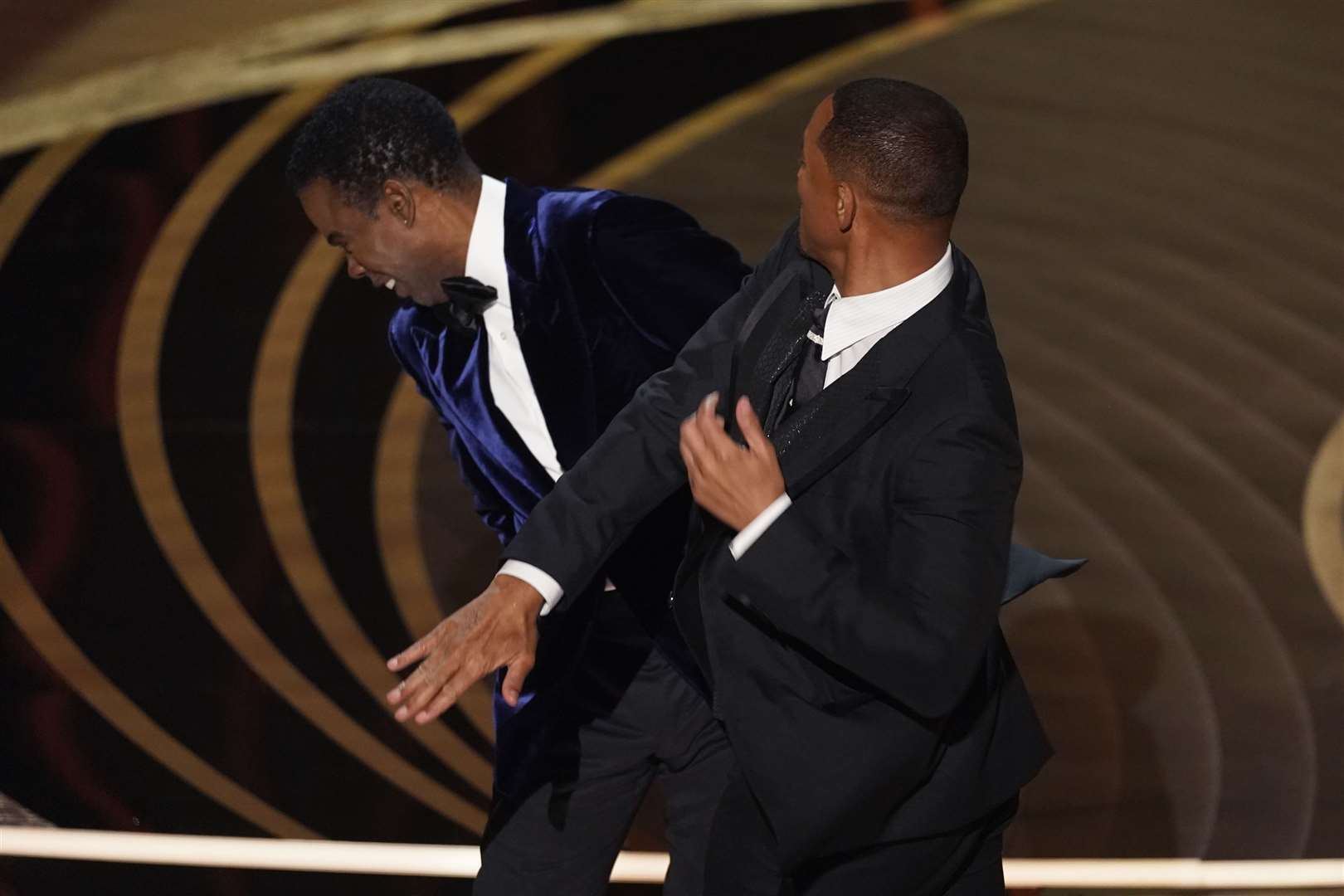 Will Smith, right, hits presenter Chris Rock on stage while presenting the award for best documentary feature at the Oscars (Chris Pizzello/AP)