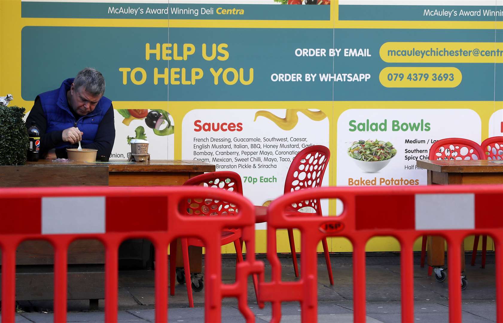 A man eats outside a shop on a quiet street in Belfast city centre as the six-week lockdown in Northern Ireland continues (Brian Lawless/PA)