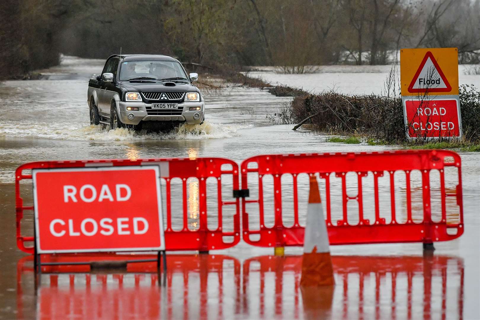 A 4×4 vehicle manages to drive through rising floodwater on the closed B1243 in Lower Applerley, Gloucestershire (PA)