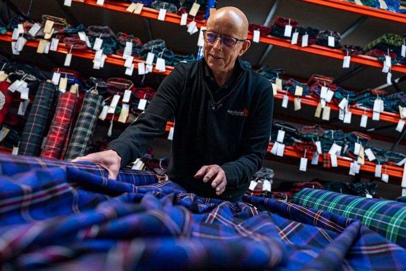 Colin Brown of Ingles Buchan examines the freshly made Interpol tartan (Interpol/PA)