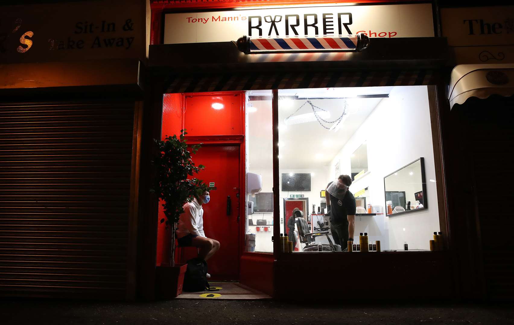 Tony Mann looks out from his shop as first customer Mitchell Wildman waits to enter before midnight (Andrew Milligan/PA)