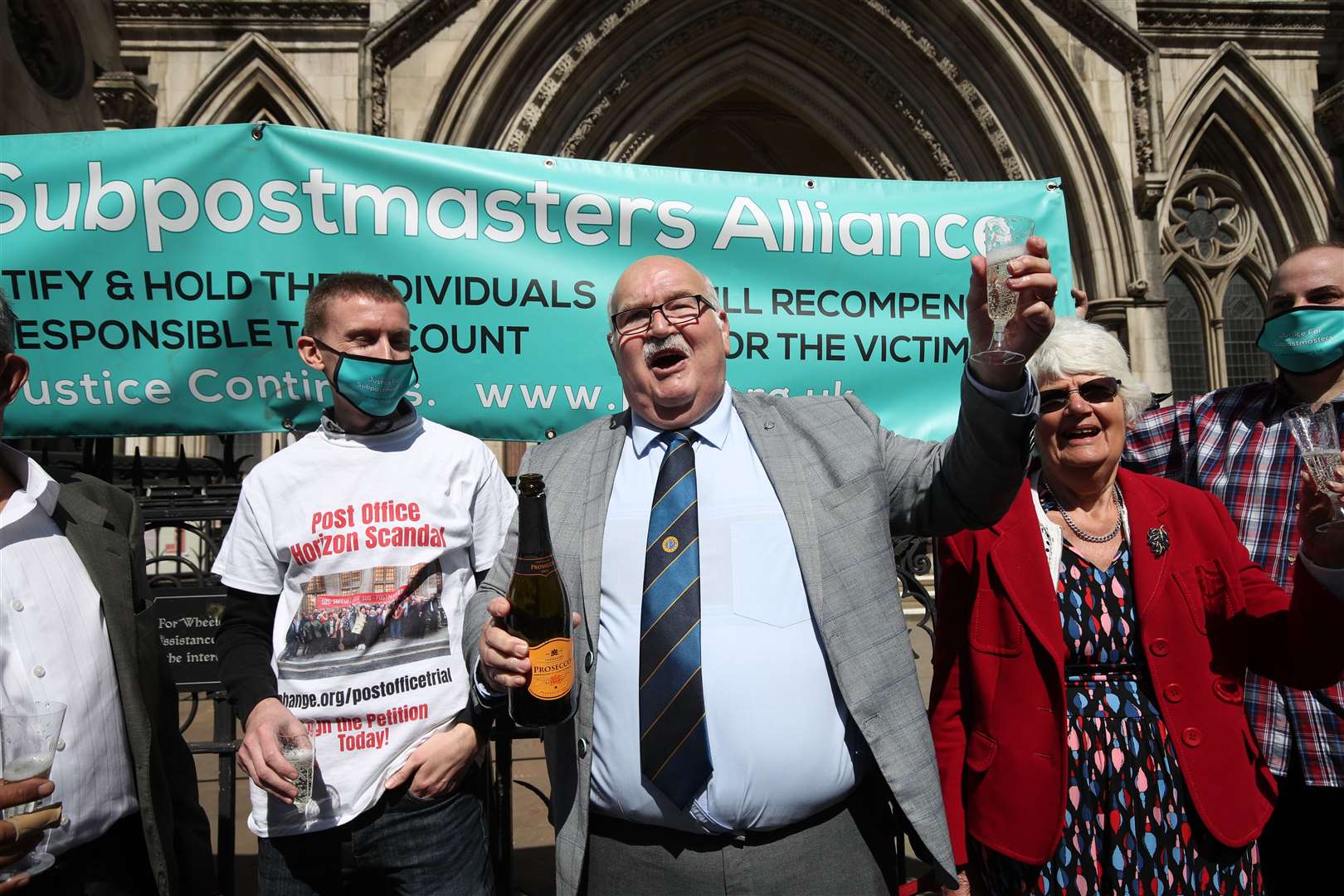 Former post office worker Tom Hedges (centre) pops a bottle of champagne in celebration outside the Royal Courts of Justice (Yui Mok/PA)