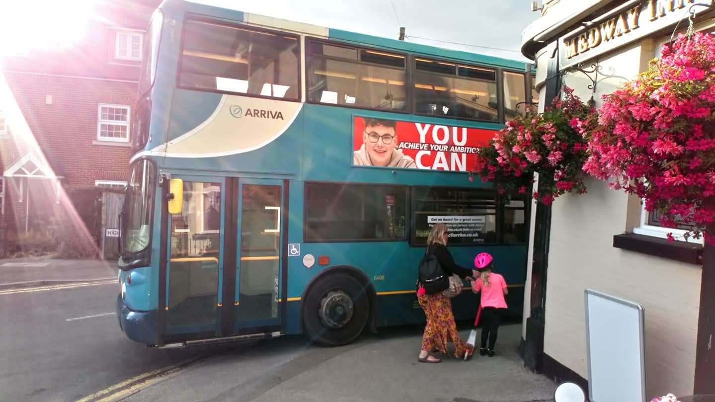 A bus mounts the pavement in front of a mother and child