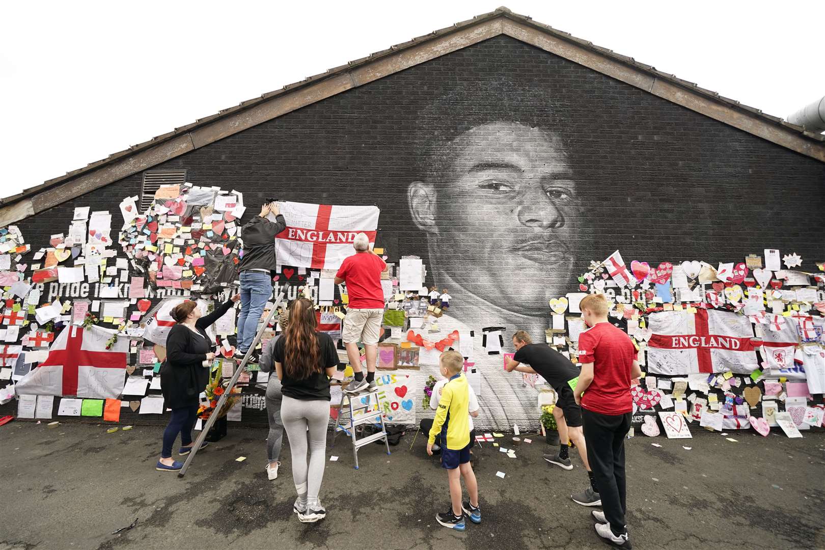 People put up flags and messages on the mural of Manchester United and England player Marcus Rashford in Withington after it had been defaced (Danny Lawson/PA)