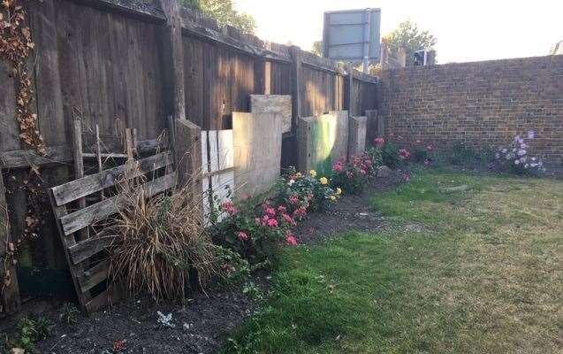 The fence is supported by a section of boards and pallets - but the flowers are colourful