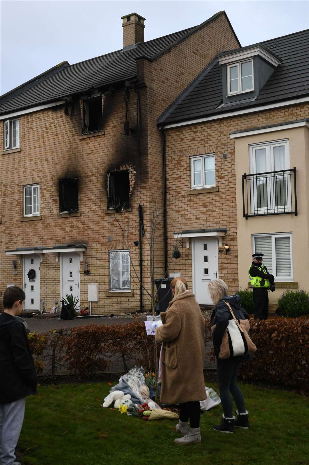 People lay flowers at the scene of a house fire on Buttercup Avenue, Eynesbury, Cambridgeshire, in which a three-year-old boy and a seven-year-old girl died (Joe Giddens/PA)