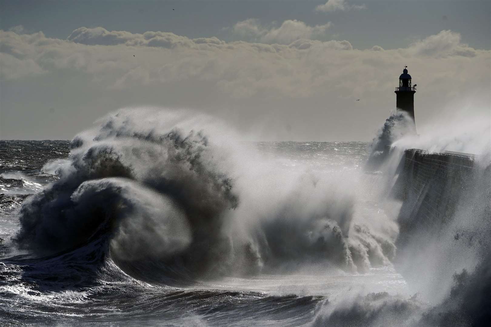 Waves crash against the Tynemouth Lighthouse on the North East coast (Owen Humphreys/PA)