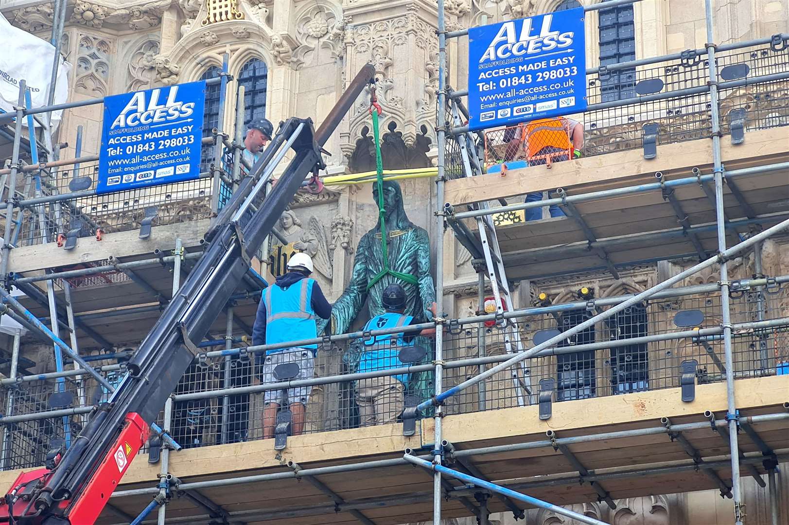 Workmen carefully install the Welcoming Christ statue