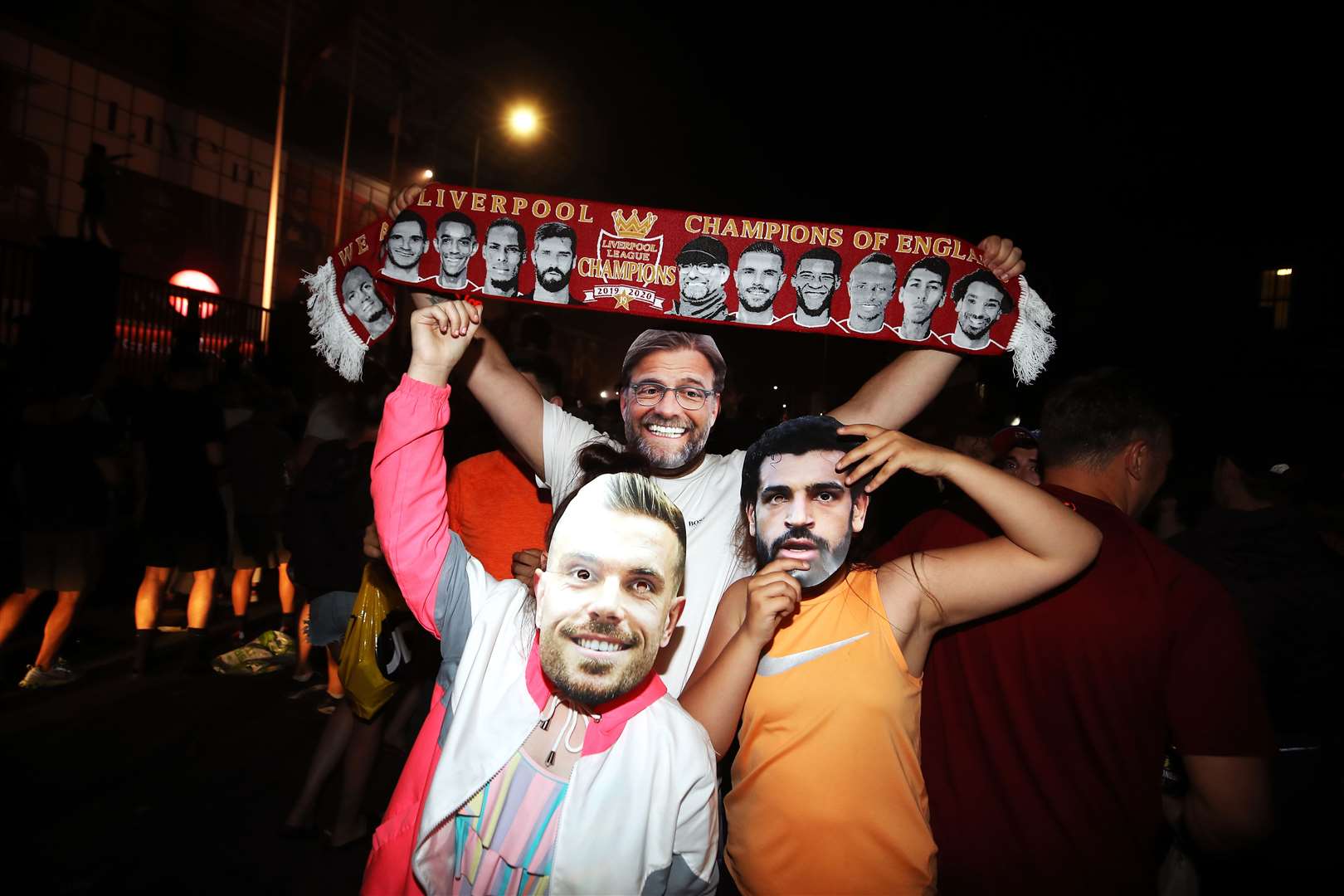 Liverpool fans wearing Jordan Henderson, Mohamed Salah and Jurgen Klopp face masks celebrate outside Anfield (Martin Rickett/PA)