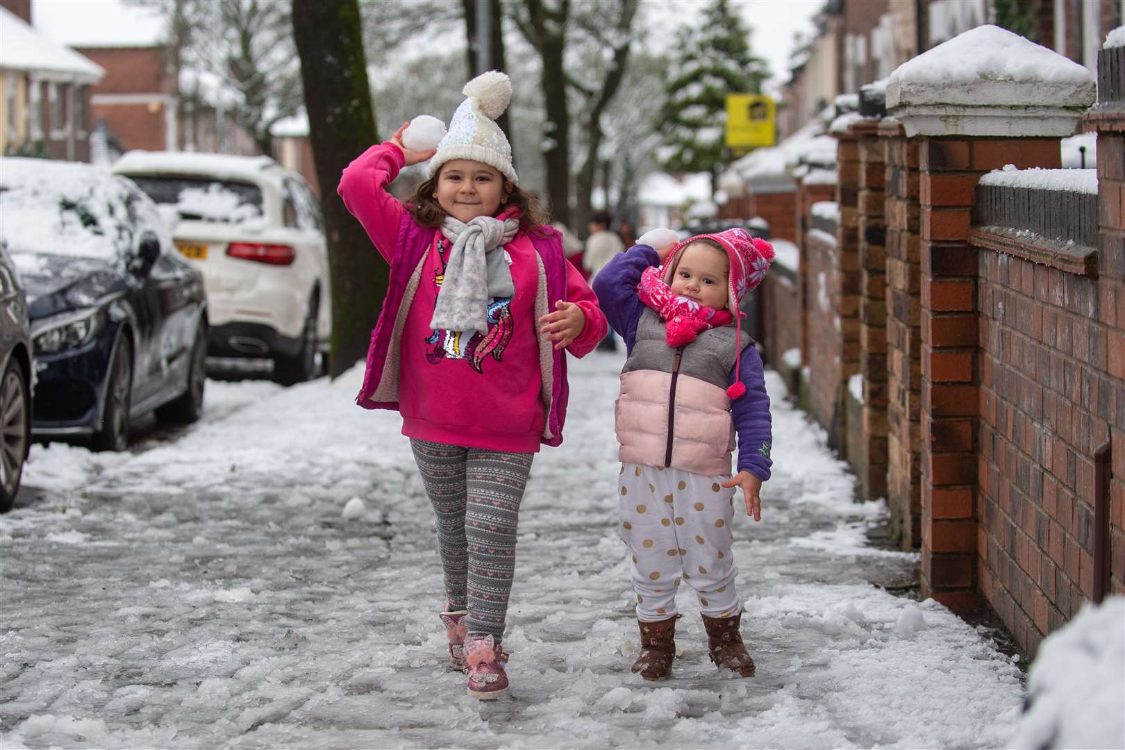 Cristina, four, and her sister Stefania, three, play with snowballs in Stoke-on-Trent, Staffordshire (Joe Giddens/PA)