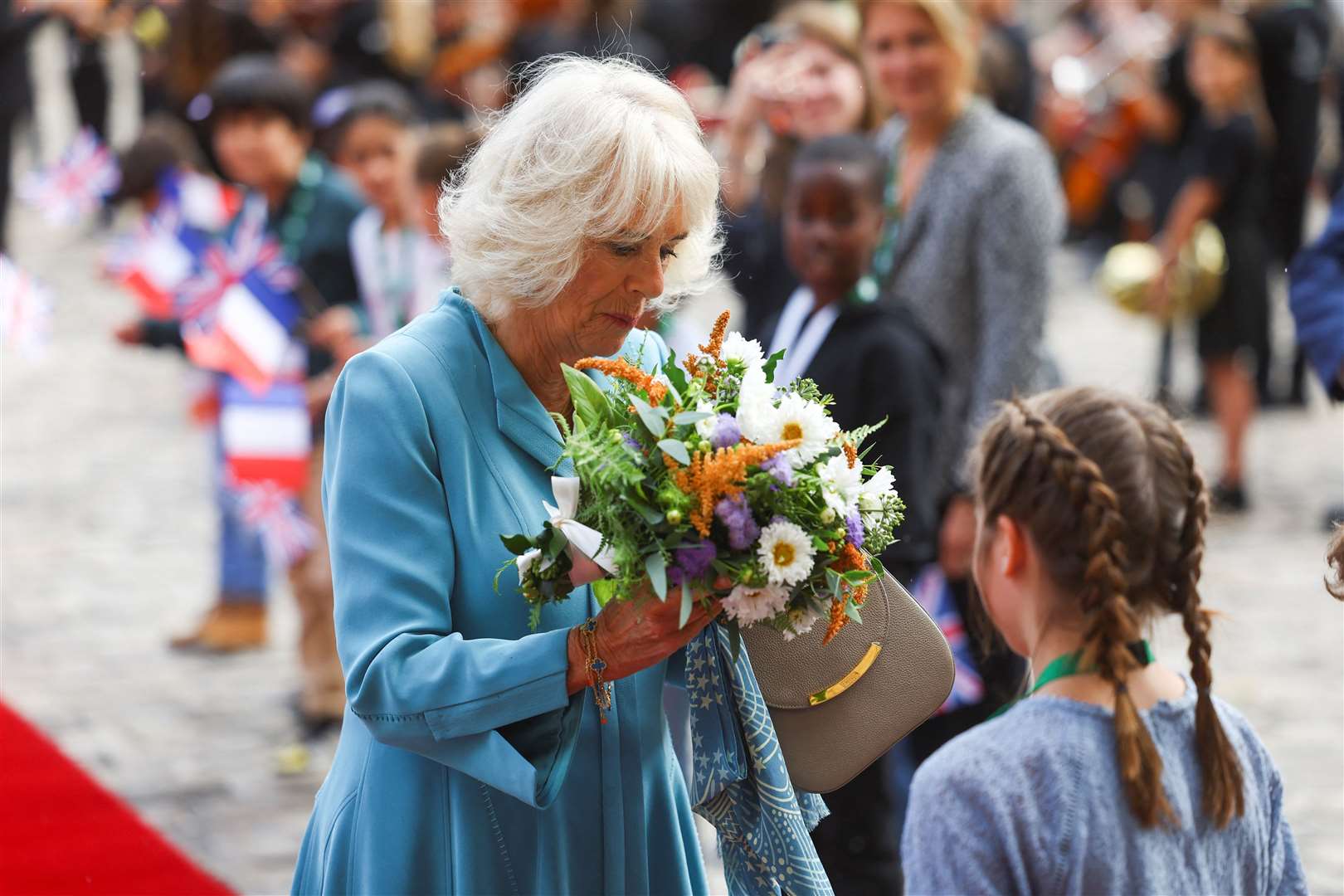 Camilla accepts a bouquet of flowers as she arrives for a visit to the Hotel de Ville in Bordeaux (Hannah McKay/PA)